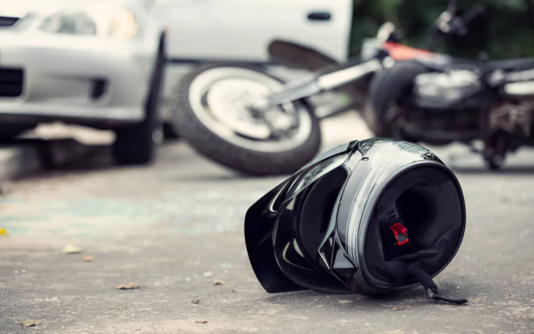 Close-up of helmet on ground, blurred motorcycle accident and car in the background
