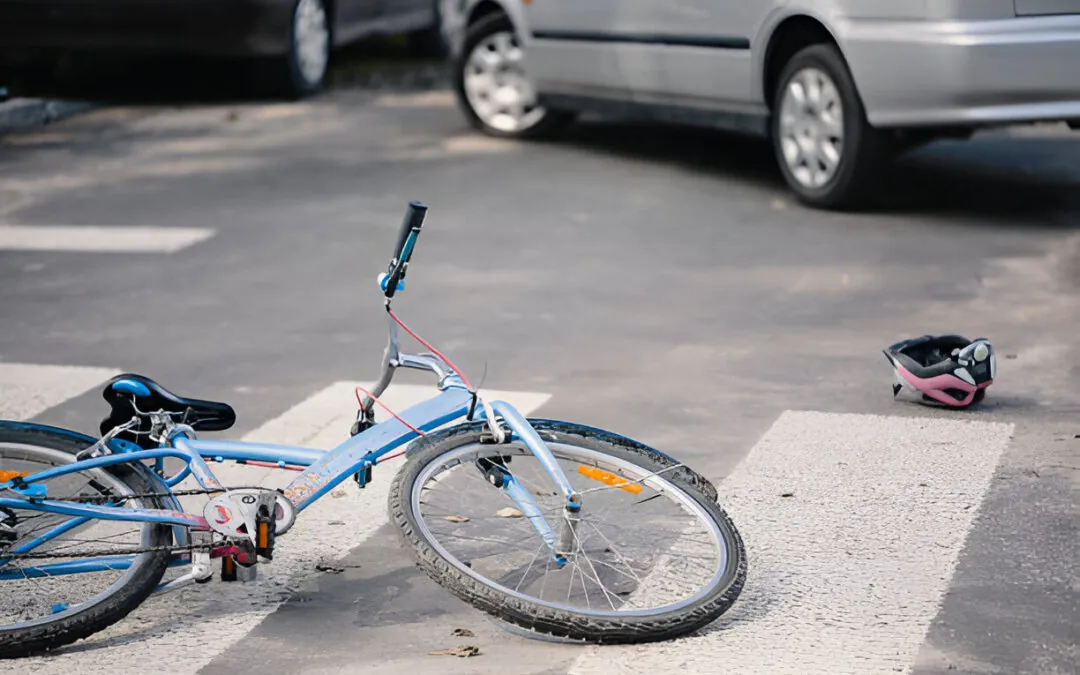 Bicycle and helmet on ground, cars in background